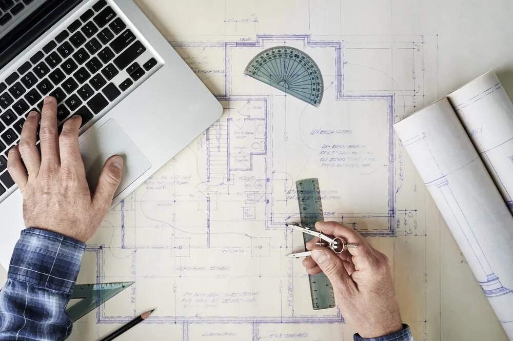 Person analyzing blueprints on a laptop - Home Drafting Services Portland